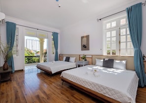Habitación de hotel con dos camas, piso de madera, balcón y vista a la ciudad.
