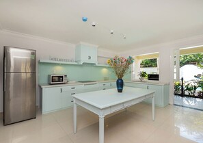 A modern kitchen with a stainless steel refrigerator, a microwave, and a white dining table.