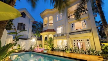 A large, multi-story building with a pool and outdoor seating area.