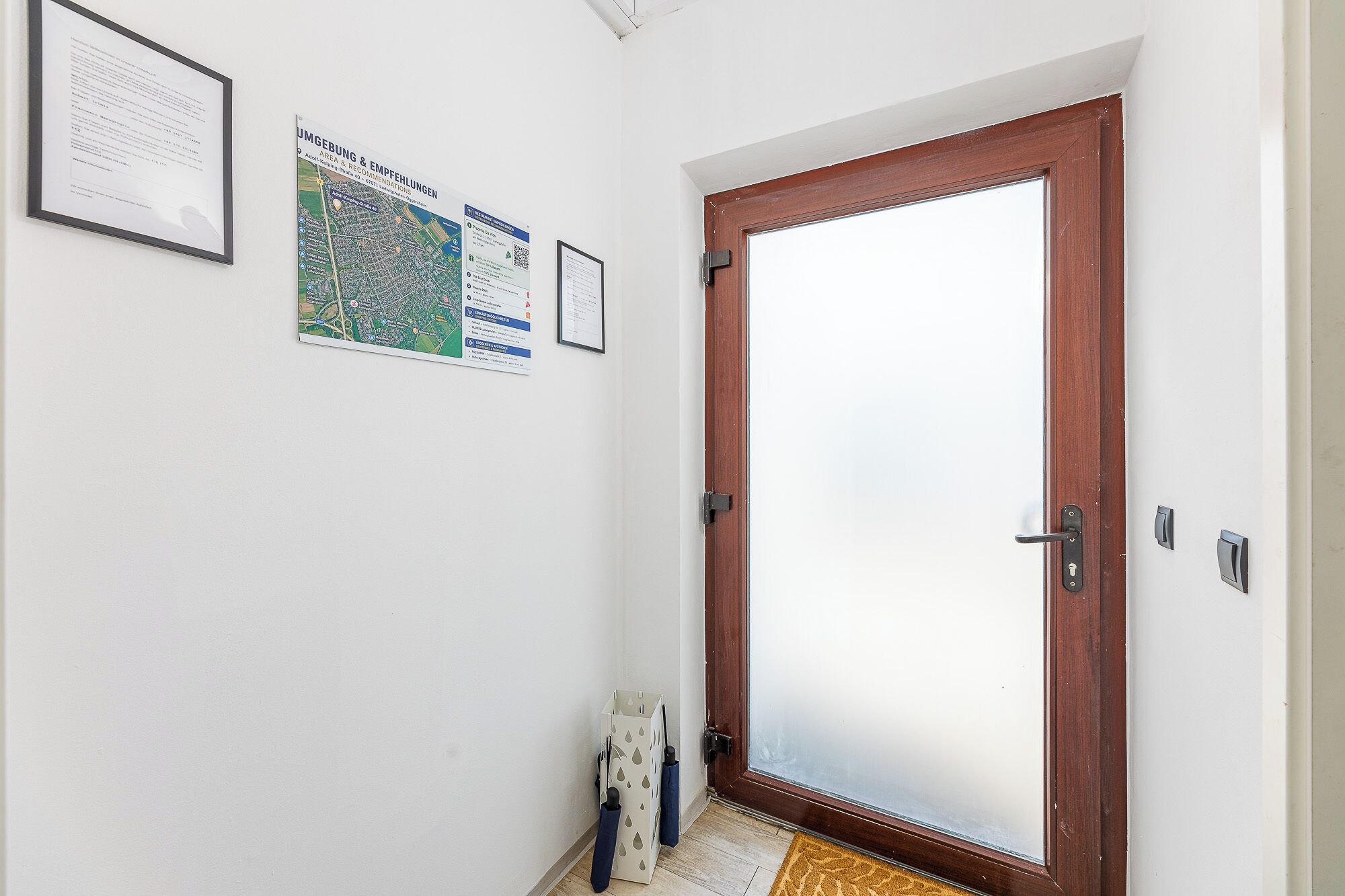 Ein Flur mit einer Holztür, einer Karte und einem gerahmten Dokument an der Wand.