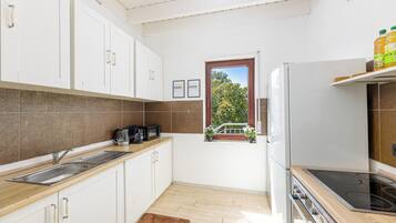 Eine Küche mit weißen Schränken, einer Holz Arbeitsplatte, einem eingebauten Ofen und einem Fenster mit Blick auf Bäume.