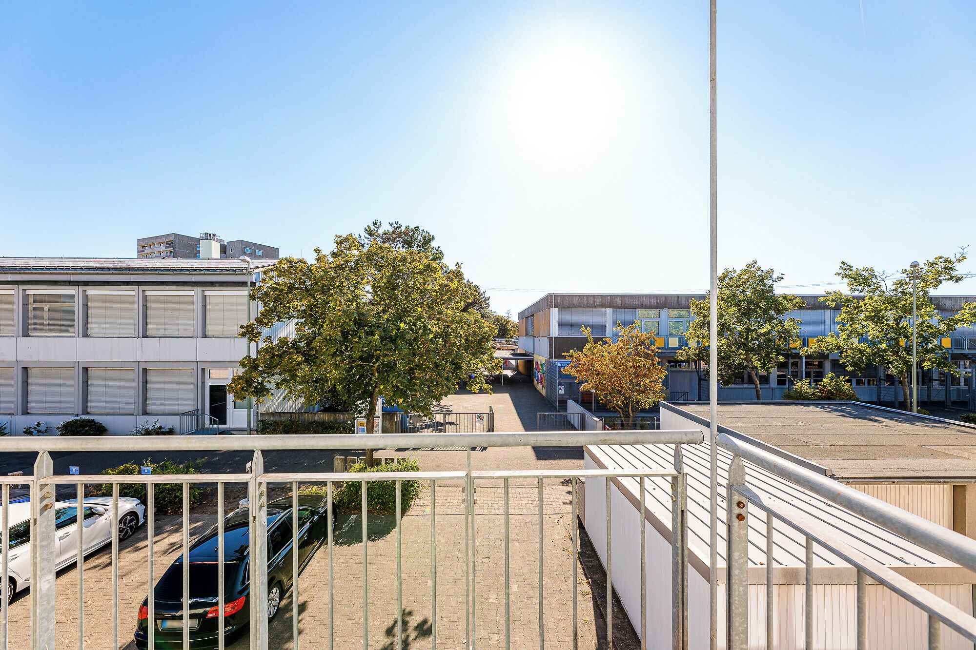 Ein Parkplatz mit Autos, ein Gebäude mit flachem Dach und einem klaren Himmel.