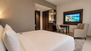 Una habitación de hotel con una cama grande, un escritorio, una silla y un televisor montado en la pared.