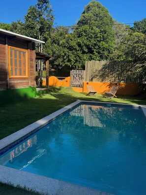 Ein Schwimmbad mit Holzterrasse und Liegestühlen.
