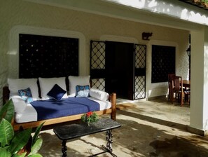 Une chambre avec un canapé-lit, une petite table avec une plante et une chaise.