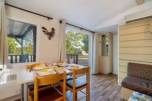 Un coin repas avec une table dressée pour quatre personnes, des chaises, un élément décoratif mural et une vue sur l’extérieur.