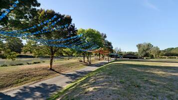 A park with a paved path, trees, and a building in the background.