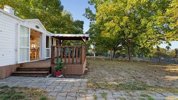 Een gelijkvloers huis met een overdekte veranda en een kleine tuin.
