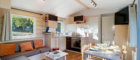 Un espacio habitable compacto con kitchenette, comedor y zona de estar.