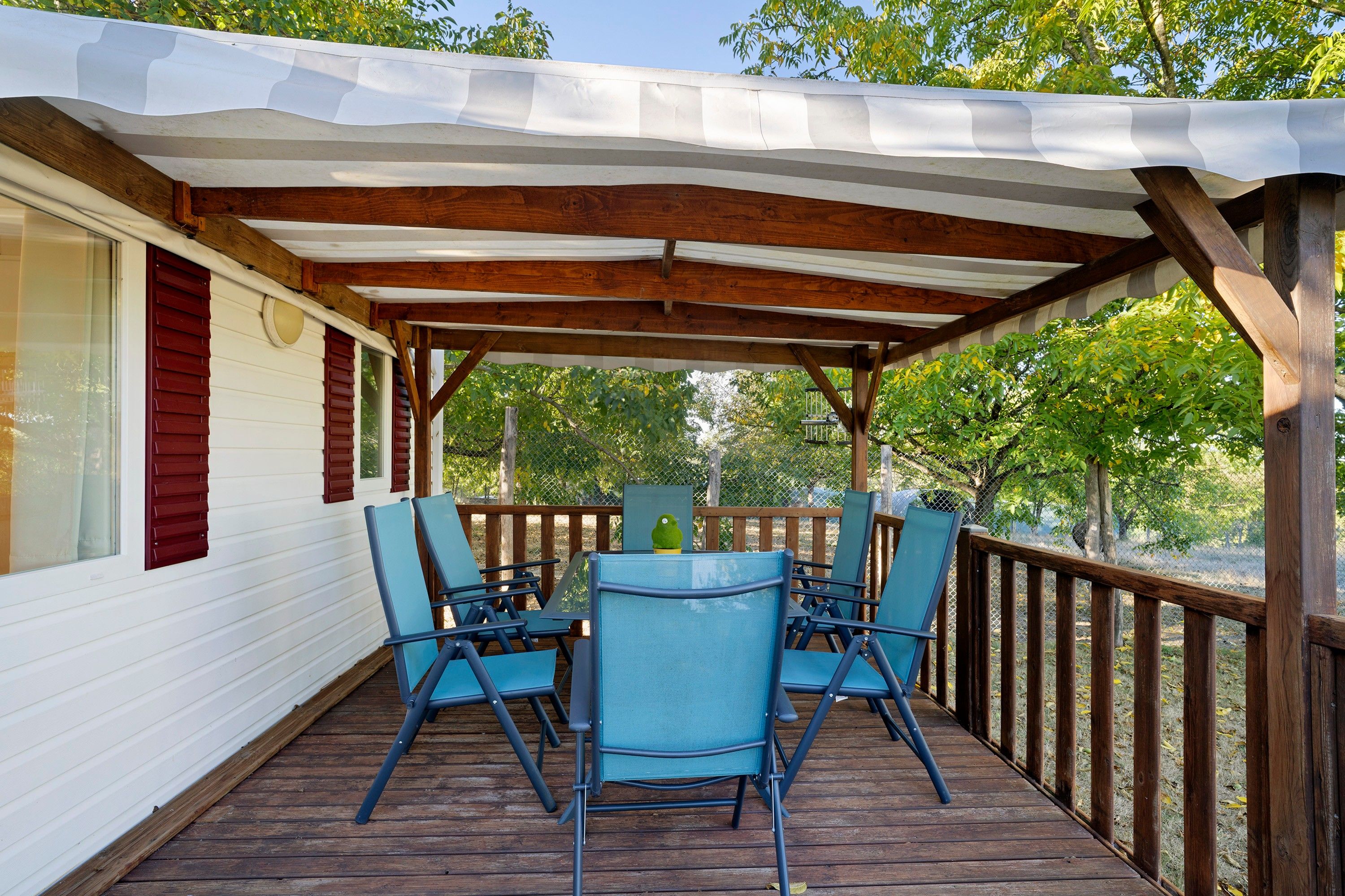 Eine Terrasse im Freien mit Holzdeck, überdachtem Sitzbereich und Blick auf Bäume.