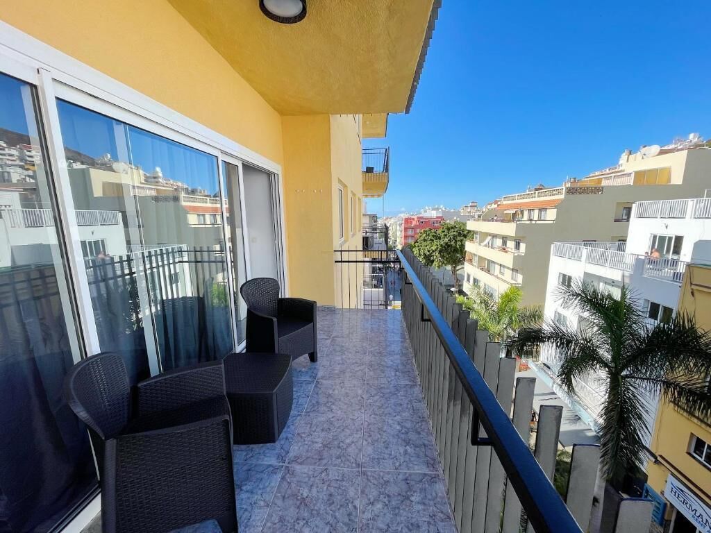 A balcony with a seating area, a view of the city, and a railing.