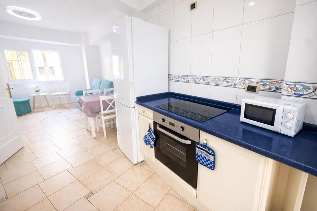 A kitchen with a blue countertop, white cabinets, a microwave, and a stove.
