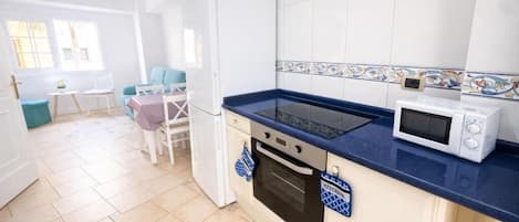 Una cocina con encimera azul, armarios blancos, un microondas y una estufa.
