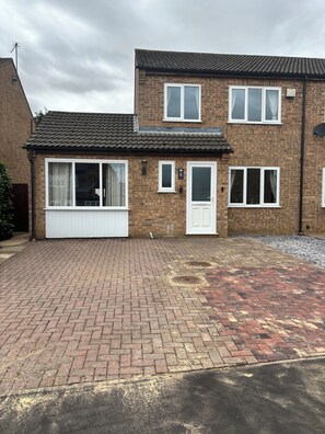 A two-story brick house with a front garage, a driveway, and a satellite dish. - Newly refurbished 4BR house w/Downstairs ensuite (Sleaford)