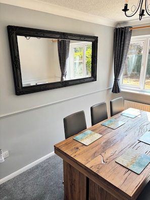 A dining area with a wooden table, chairs, and a large mirror on the wall. - Newly refurbished 4BR house w/Downstairs ensuite (Sleaford)