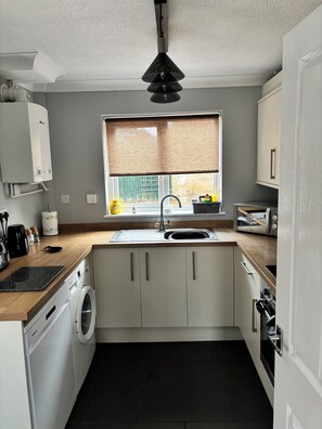 A compact kitchen with a washing machine, a sink, and a microwave. - Newly refurbished 4BR house w/Downstairs ensuite (Sleaford)