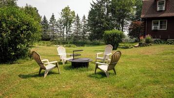 Un espace extérieur aménagé avec une pelouse, comprenant quatre fauteuils Adirondack et une table ronde.