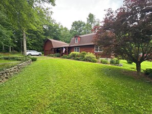 A two-story log cabin with a red roof, surrounded by a well-maintained lawn and trees. - Private Log Cabin Retreat with all Amenities in Greene, NY. (Greene)