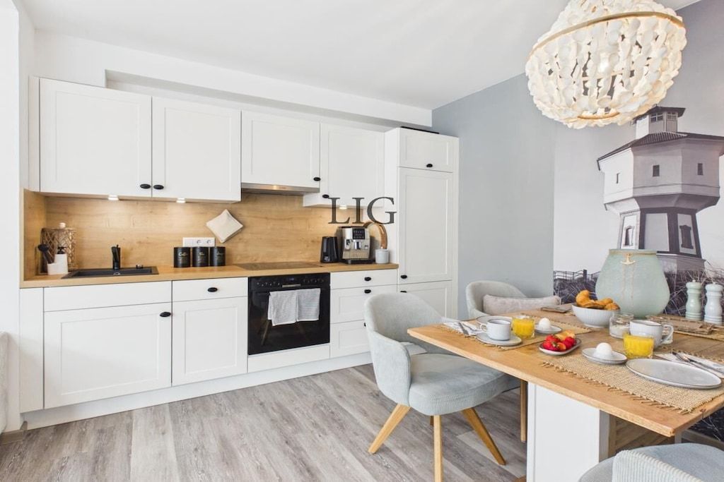 A modern kitchen with white cabinetry, a wooden countertop, and a dining area with a table set for breakfast.