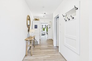 A hallway with a wooden floor, a mirror, a table with a lamp, and a coat rack. - Holiday apartment Norderloog 2 (Langeoog)