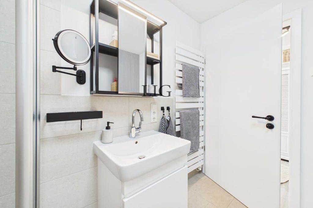 Uma casa de banho moderna com uma pia branca, um espelho e um porta-toalhas.