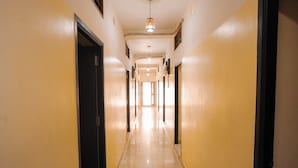 A hotel hallway with doors on both sides, a tiled floor, and a hanging light fixture. - Vel Ohm Homestay (Puducherry)