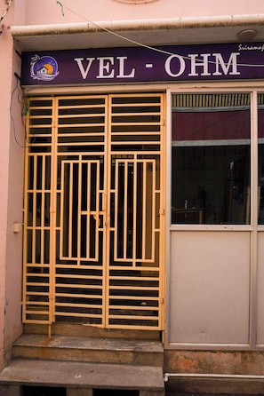 A building with a sign reading 'VEL-OMH' above a large metal gate. - Vel Ohm Homestay (Puducherry)
