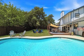 Ein Garten mit Schwimmbad, Gartenmöbeln und einem Haus.