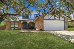 A two-story house with a garage, a front porch, and a well-maintained lawn. - Pool Haven | Hot Tub Fire Pit Game Room Sleeps 18 (San Antonio)
