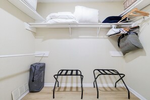A compact room with a bed, a drying rack, a small stool, and a bag on the floor. - Pool Haven | Hot Tub Fire Pit Game Room Sleeps 18 (San Antonio)