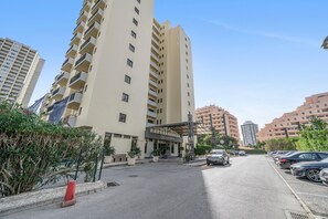 A multi-story hotel with a covered entrance, parking lot, and surrounding greenery. - Apartment 'T1 Mar De Amarilis' with Sea View, Wi-Fi and Air Conditioning (Portimão)