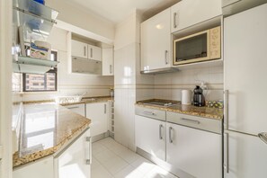 A modern kitchen with white cabinets, a granite countertop, a built-in microwave, and a stainless steel refrigerator. - Apartment 'T1 Mar De Amarilis' with Sea View, Wi-Fi and Air Conditioning (Portimão)