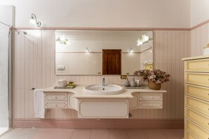 Een badkamer met een grote spiegel, twee wasbakken, een opbergmeubel met lades en een kastje met decoratieve objecten.
