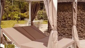 A covered outdoor seating area with a bench and a table, surrounded by a stone wall and a clear sky. - La Tenuta il Castagno (Terzigno)