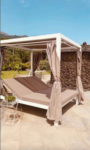 A covered outdoor seating area with a bench and a table, surrounded by a stone wall and a clear sky. - La Tenuta il Castagno (Terzigno)