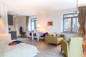 A hotel room with a bed, a desk, two chairs, a sofa, and a window. - Villa by the Swan Pond (Fehmarn)