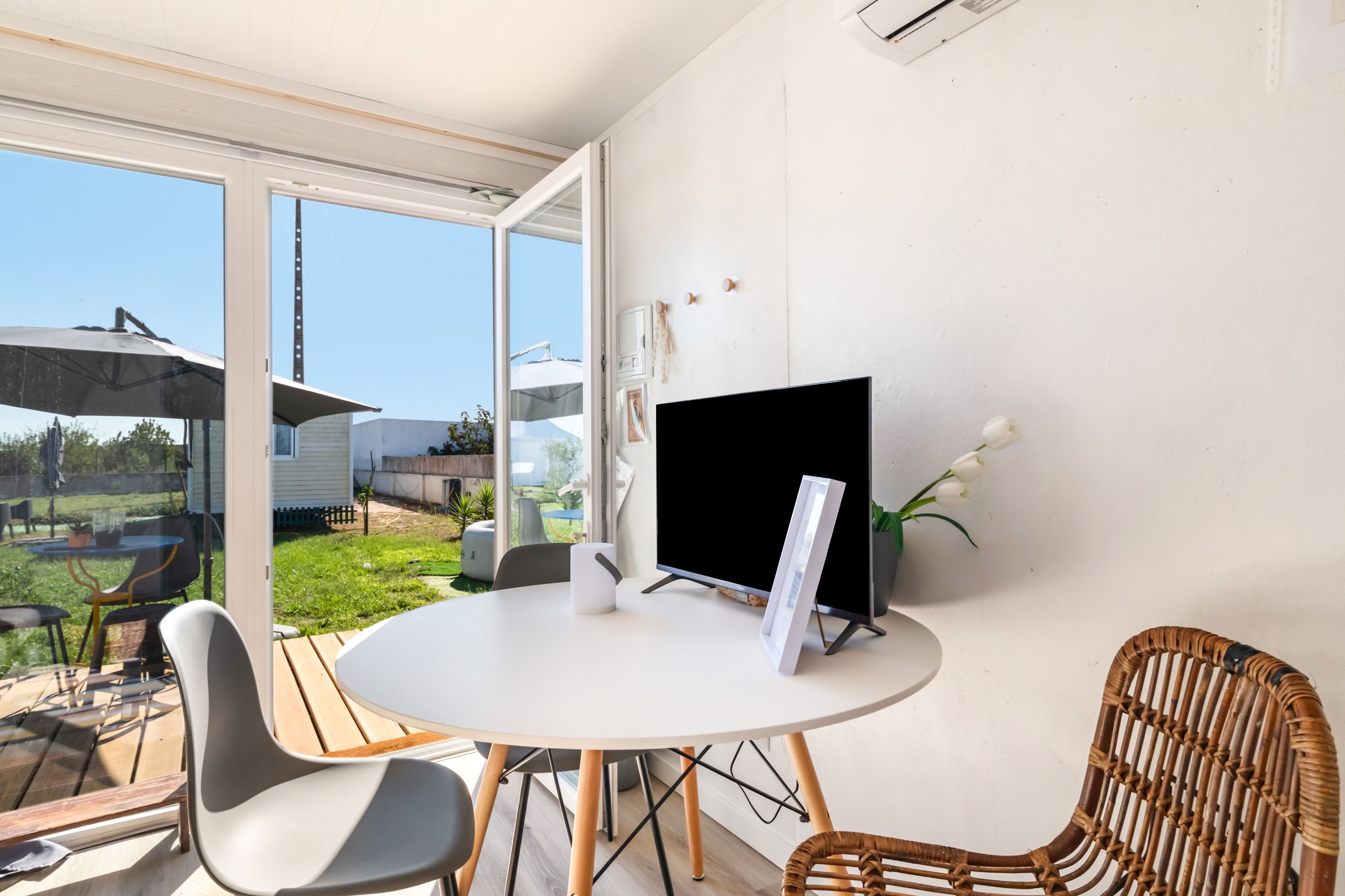 Ein modernes Zimmer mit einem runden Tisch, zwei Stühlen, einem Fernseher und Blick ins Freie.