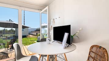 A modern room with a round table, two chairs, a TV, and a view of the outdoors.