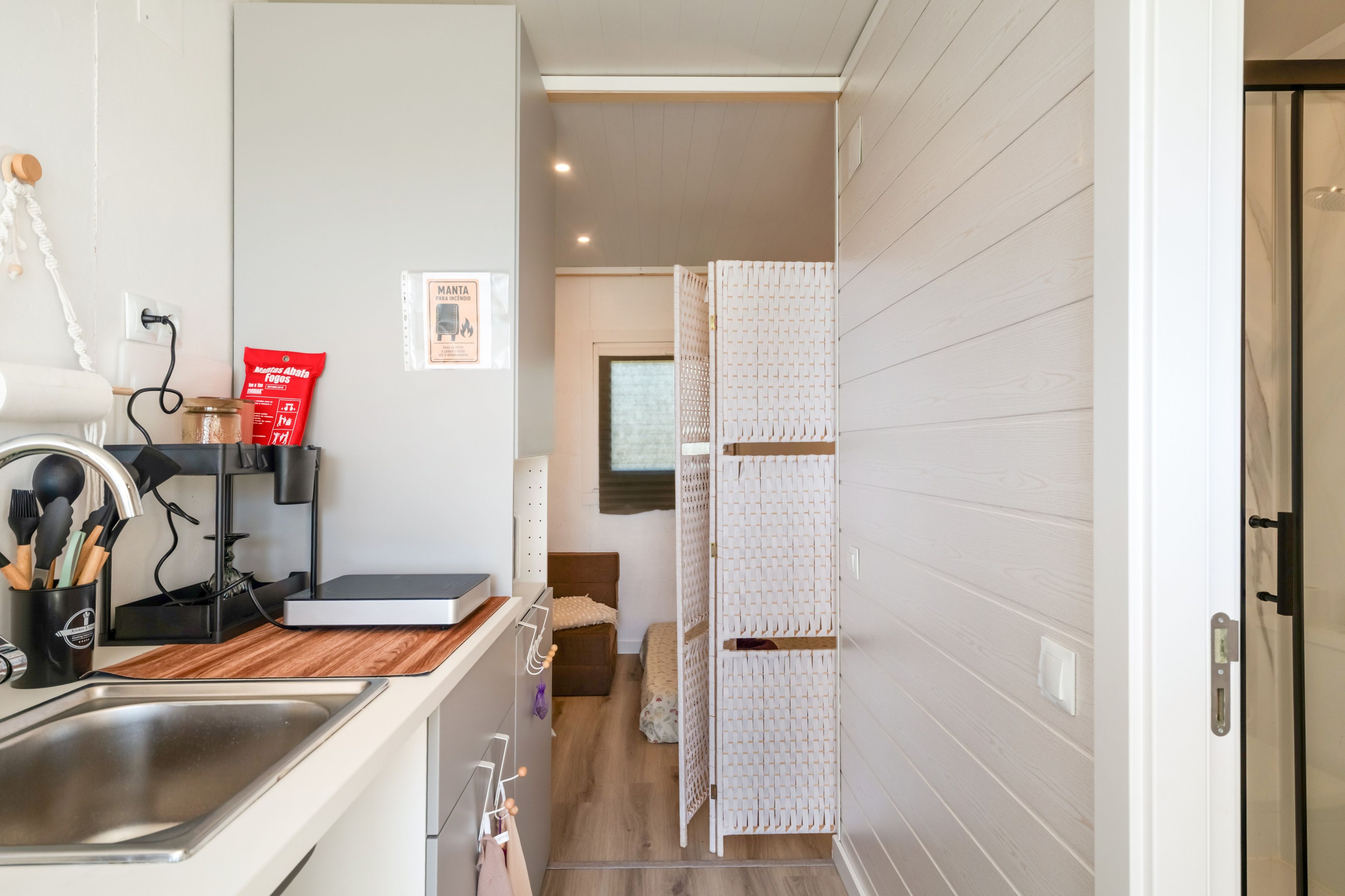 A modern kitchen with a sink, countertop, and a cabinet with utensils.