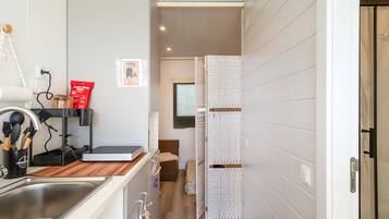 A modern kitchen with a sink, countertop, and a cabinet with utensils.