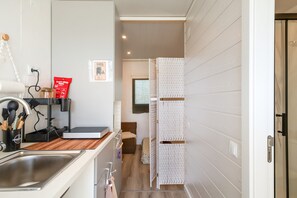 A modern kitchen with a sink, countertop, and a cabinet with utensils.