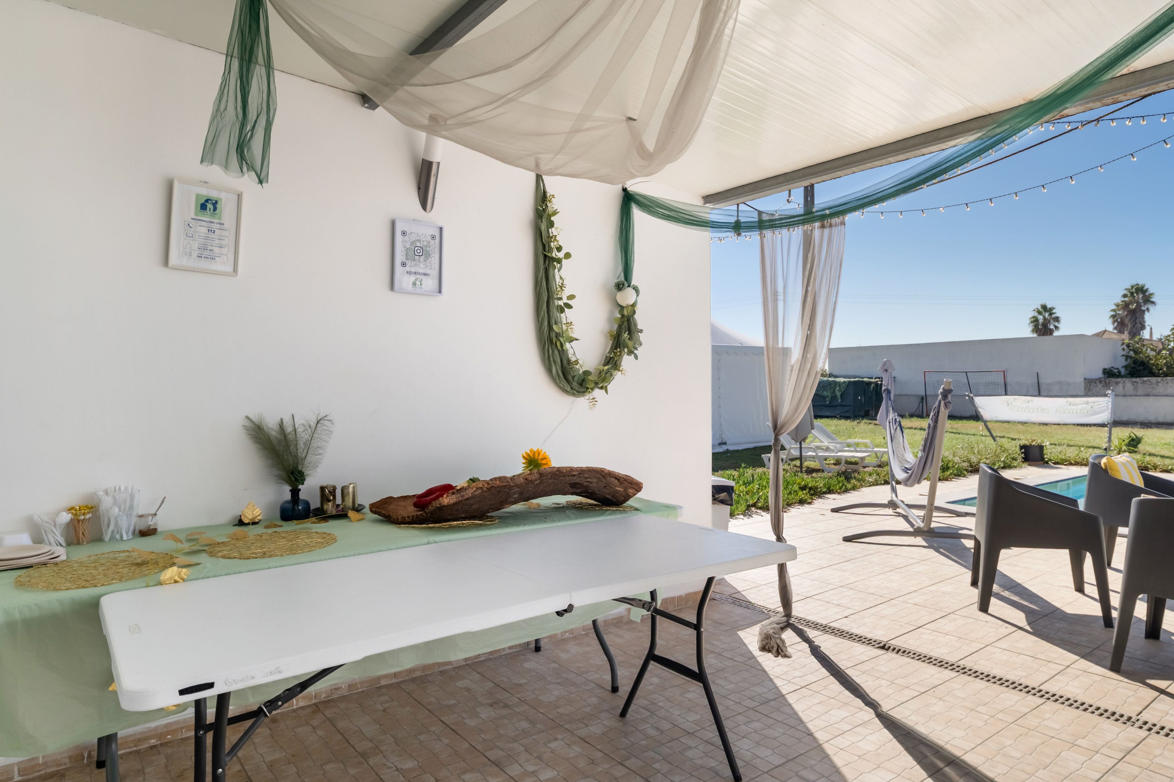 An outdoor patio with a dining table, chairs, and a pool area.