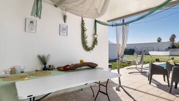 An outdoor patio with a dining table, chairs, and a pool area.