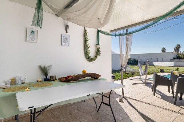 An outdoor patio with a dining table, chairs, and a pool area.