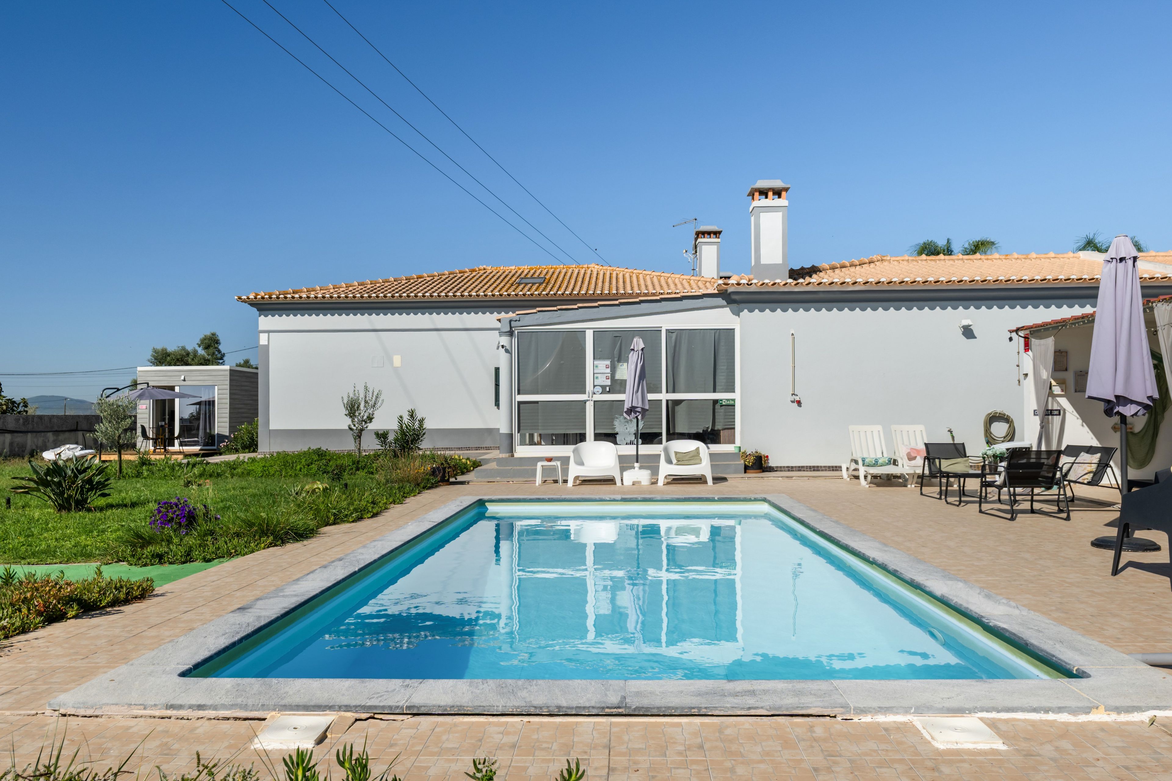 Une maison moderne dotée d’une piscine, d’un espace salon extérieur et offrant une vue sur un ciel dégagé.