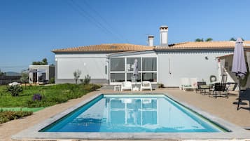 Une maison moderne dotée d’une piscine, d’un espace salon extérieur et offrant une vue sur un ciel dégagé.