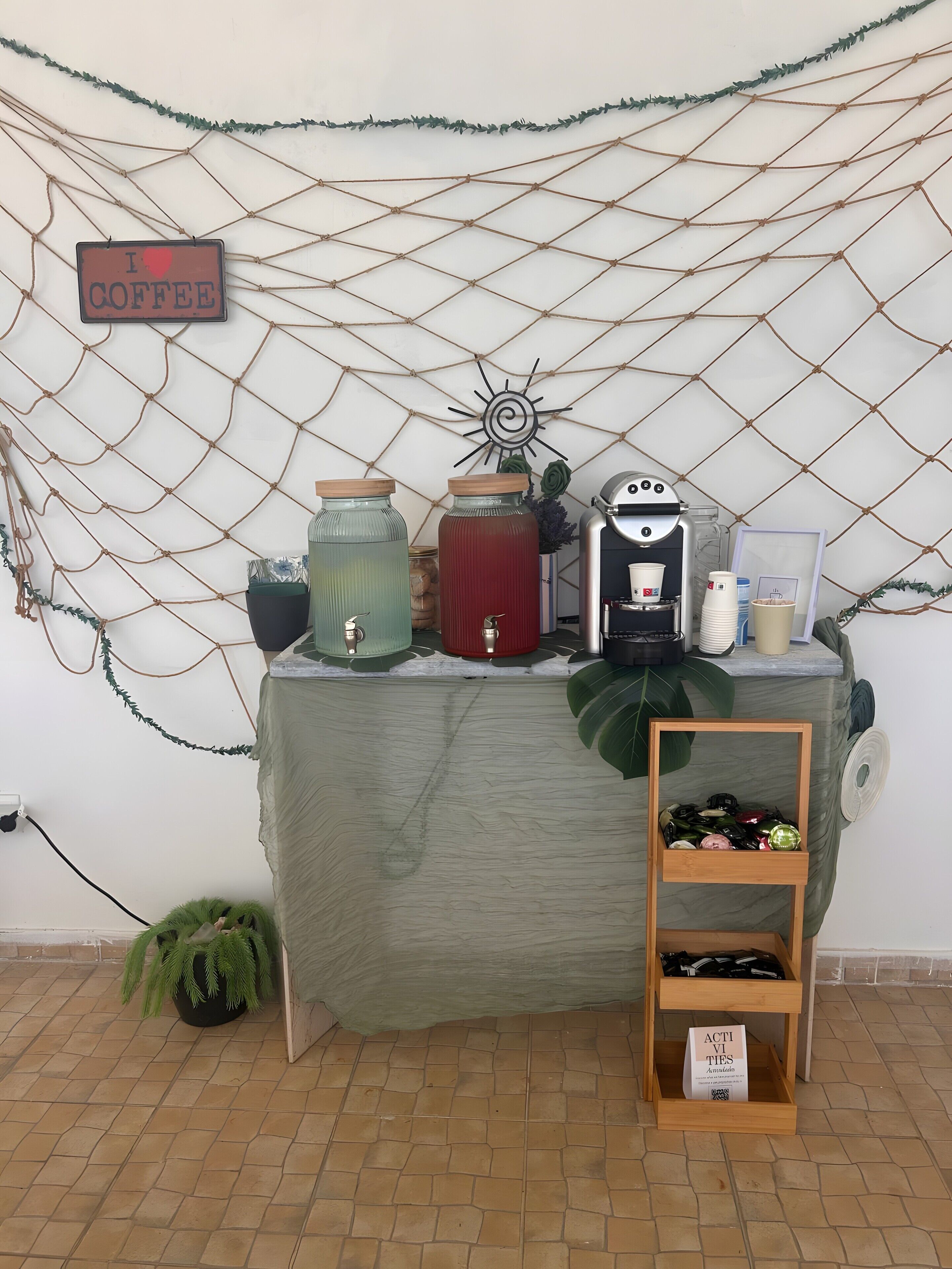 Una estación de café con un cartel, tarros, una máquina de café y una repisa de madera con botellas.