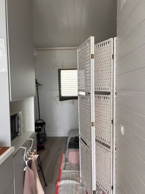 A room with a bed, a window, a radiator, and a wall-mounted rack. - Tiny House with Shared Pool, Wi-Fi, and Air Conditioning (Palmela)