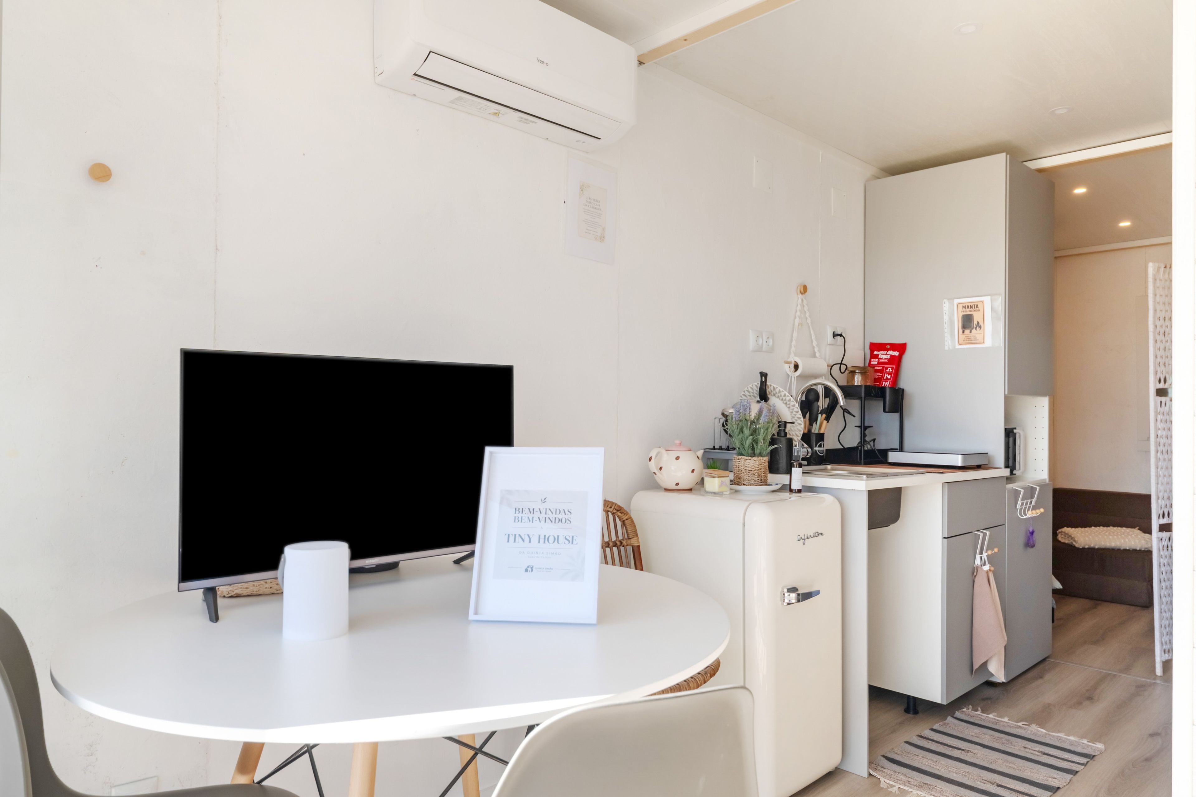 Une cuisine moderne avec un coin repas, un réfrigérateur et un téléviseur à écran plat.