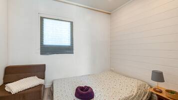 Una habitación con una cama, una silla, un ventanal y una lámpara.